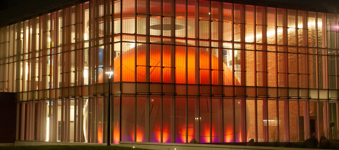 a building with glass walls anda large orange illuminated dome inside